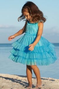 Girl dressed in a baby blue cotton dress with white shoes and a matching hair bow.